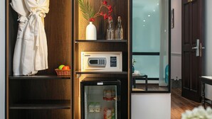 Una habitación moderna con un armario de madera, microondas, un refrigerador pequeño y una zona de comedor con mesa y sillas.