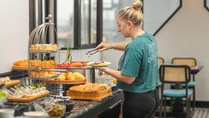Montaje de bufé con diferentes alimentos y una persona atendiendo.