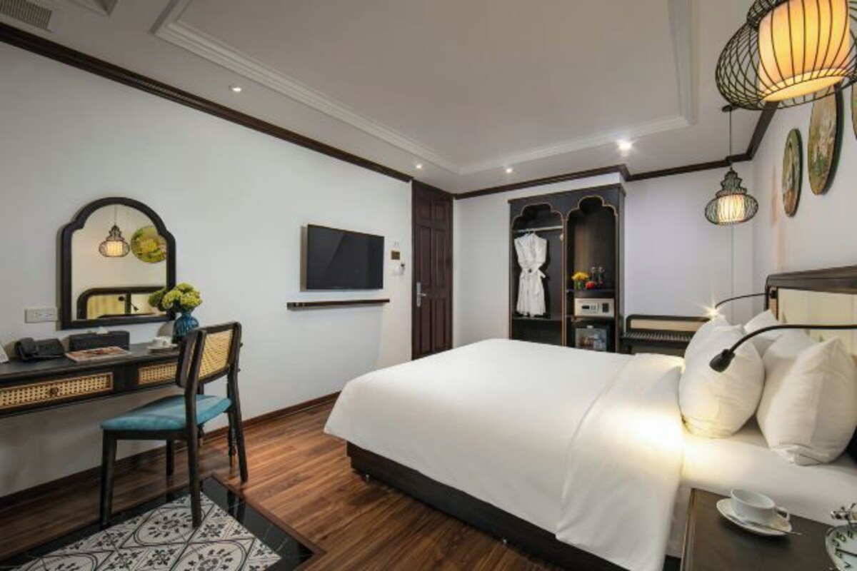 Una habitación de hotel con una cama grande, un escritorio con silla, televisión y armario.