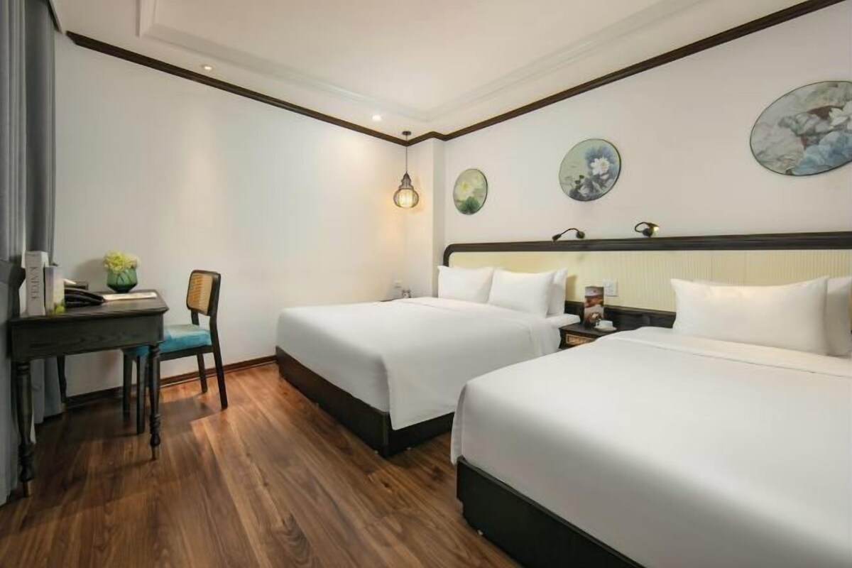 A hotel room with two beds, a desk, a chair, and a nightstand.
