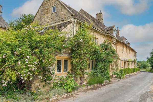 A stone house with a steeply pitched roof, a small window, and a door.