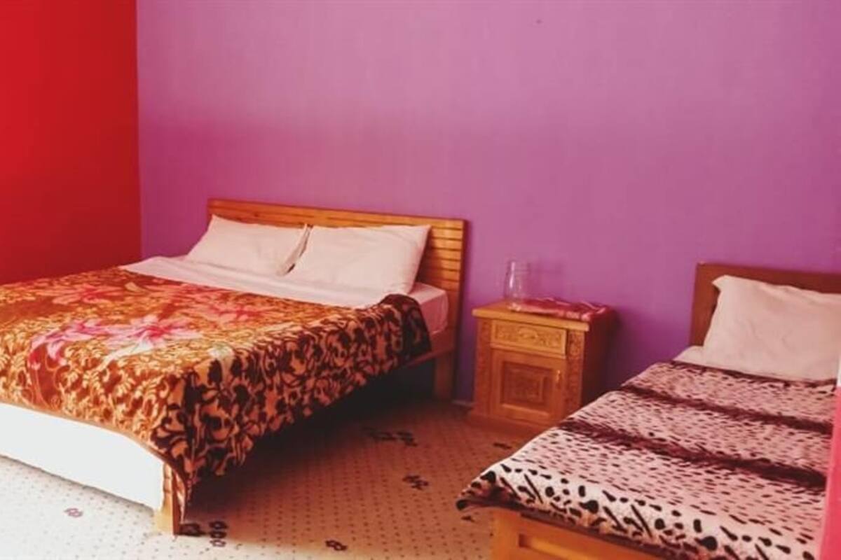 A bedroom with a bed, a nightstand, and a window with curtains.