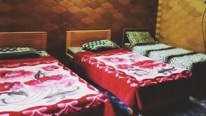 Una habitación con tres camas, cada una con una colcha estampada con motivos florales. Las paredes presentan un diseño tipo panal.
