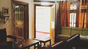 Una habitación con ventilador de techo, un sofá, una mesa y una puerta que da a otra estancia.