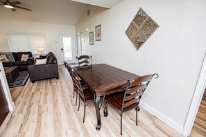 A dining area with a wooden table and chairs, a sofa, and a decorative wall piece.