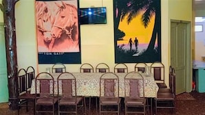 A dining area with a long table and chairs, a poster of a horse, and a sunset scene. - Indus Hotel Shangla (Besham City)