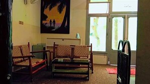 A room with two wooden sofas, a small table, and a painting of a sunset. - Indus Hotel Shangla (Besham City)