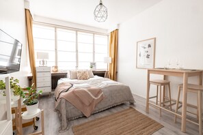 A bedroom with a bed, bedside tables, a desk, and a chair.