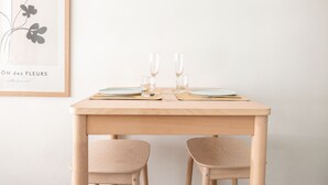A minimalist dining setup with a wooden table, two chairs, and a framed botanical print on the wall. - 2ndhomes Modern Studio in the Center (Helsinki)