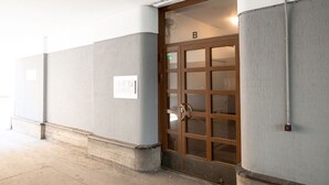 A building entrance with a door marked 'B', a light fixture above the door, and a wall-mounted light switch. - 2ndhomes Modern Studio in the Center (Helsinki)
