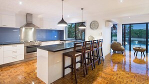 Een moderne keuken met een centraal eiland, roestvrijstalen apparatuur en een groot raam.