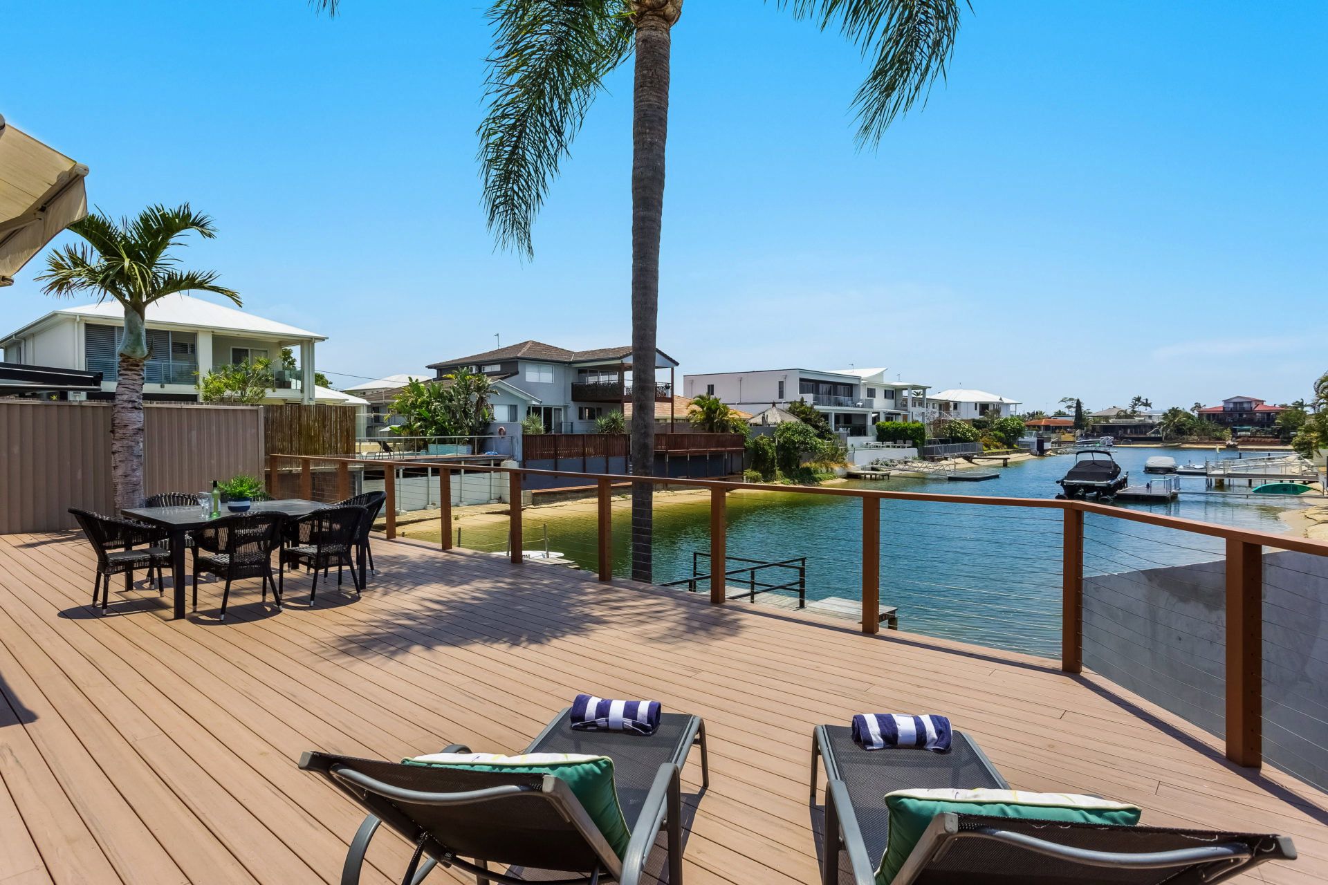 Eine Terrasse mit Liegestühlen, einem Tisch und Blick auf eine Marina mit Booten.