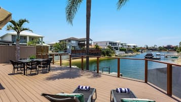 A deck with lounge chairs, a table, and a view of a marina with boats.