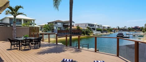 Eine Terrasse mit Liegestühlen, einem Tisch und Blick auf eine Marina mit Booten.