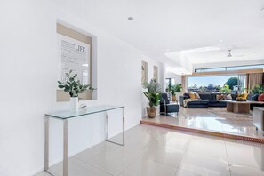 Un salón moderno con una mesa consola de cristal, un conjunto de sofá negro y un amplio ventanal con vistas a la ciudad.