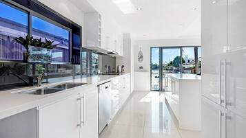 A modern kitchen with white cabinets, a stainless steel sink, and a view of the outside.