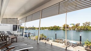 A modern outdoor lounge area with tiered seating, a view of a river, and a cityscape in the background. - Surfers Paradise Escape (Huge Heated Pool) (Gold Coast)