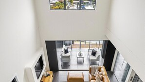 Ein modernes Wohnzimmer mit großem Fenster, einer Sofagarnitur, einem Couchtisch und einem Kamin.