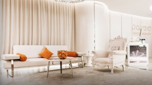 Ein modernes, stilvoll eingerichtetes Zimmer mit einem weißen Sofa, einem runden Tisch und einem klassischen Sessel.