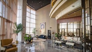Eine geräumige Lobby mit hoher Decke, großen Fenstern und einem polierten Marmorboden.