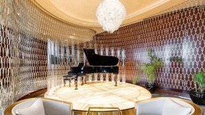 Eine luxuriöse Lobby mit einem Flügel, stilvoller Sitzgelegenheiten und einem dekorativen Kronleuchter.