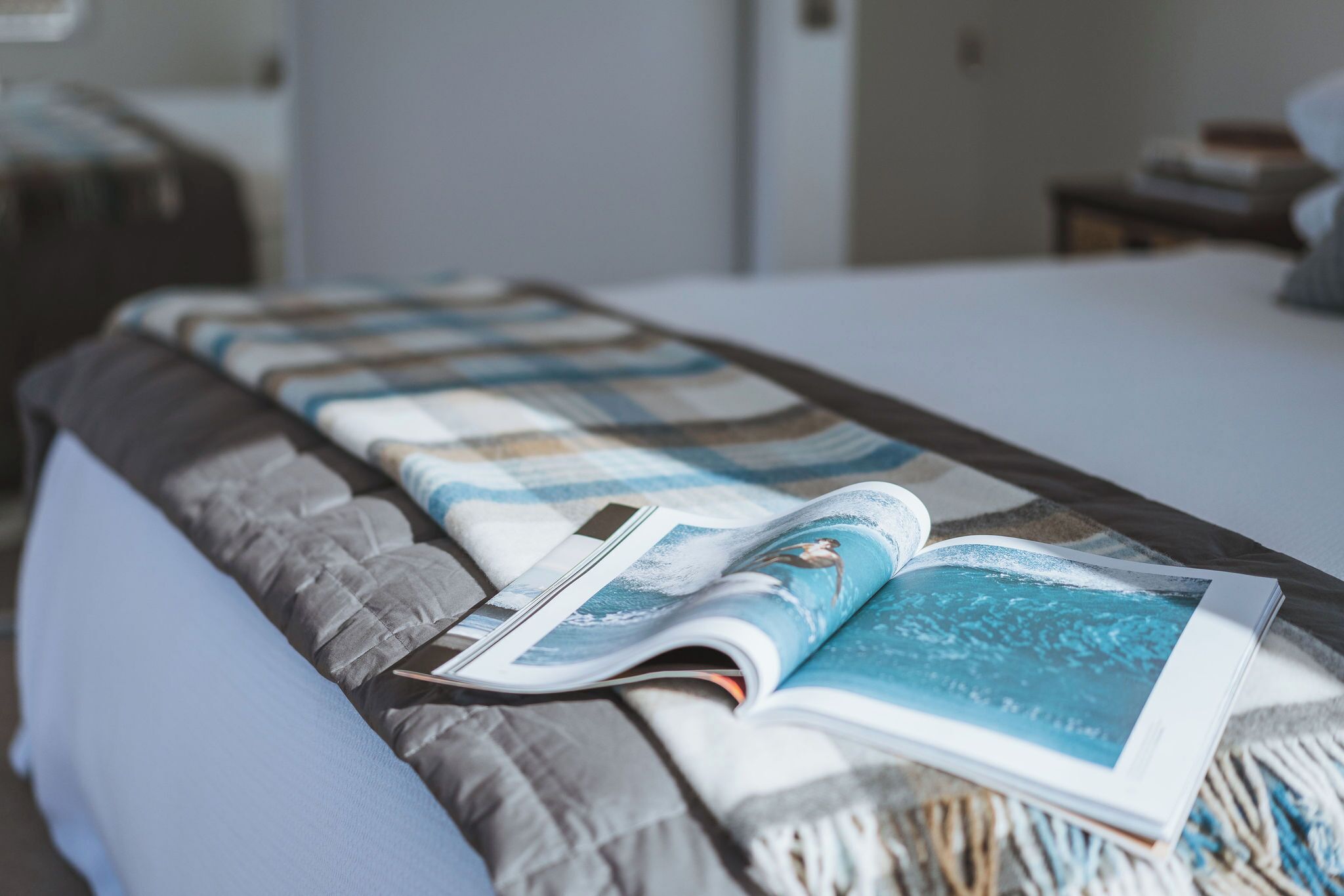 A bed with a striped blanket and a magazine.