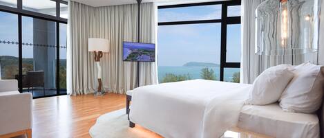 Habitación de hotel moderna con una cama grande, televisor de pantalla plana y vista al mar.