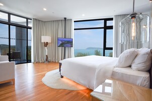 Ein modernes Hotelzimmer mit einem großen Bett, einem Flachbildfernseher und Meerblick.
