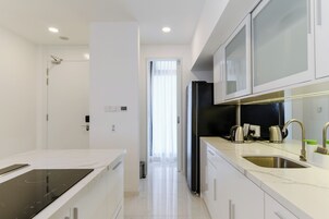 Una cocina moderna con armarios blancos, un refrigerador negro y un lavamanos de acero inoxidable.