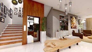A modern living room with a wooden staircase, a large wooden coffee table, and a bookshelf filled with books and decorative items.