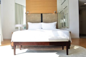 Una cama grande con cabecera de madera, una mesita de noche y un espejo en la pared.