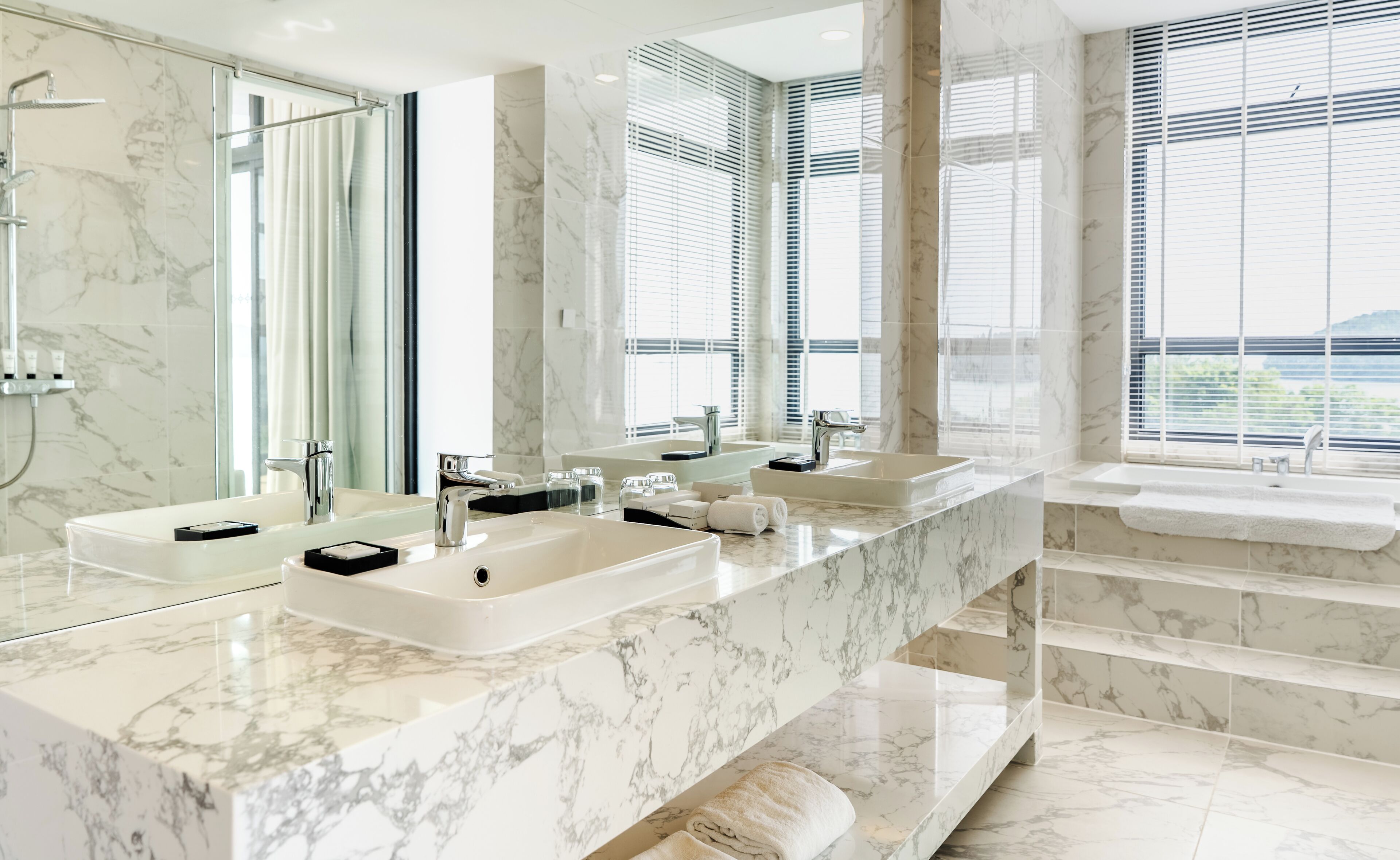 A modern bathroom with two sinks, a large mirror, and a shower.