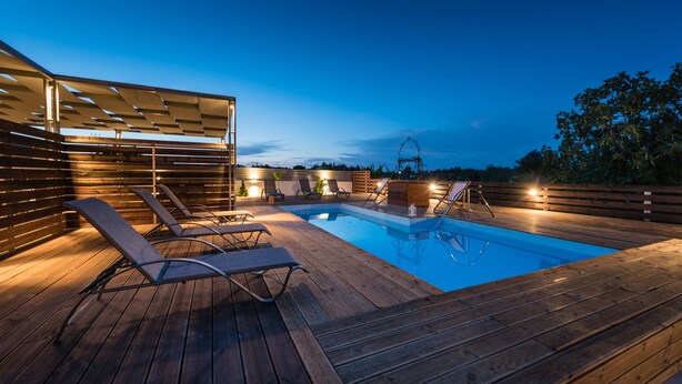 A wooden deck with a swimming pool, lounge chairs, and a pergola. - Amygdalia Villa (Zakynthos)