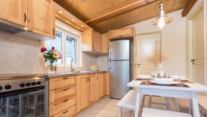 A kitchen with wooden cabinets, a stainless steel refrigerator, and a dining table set for four. - Amygdalia Villa (Zakynthos)