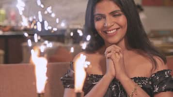 A person seated at a table with a birthday cake featuring lit candles.