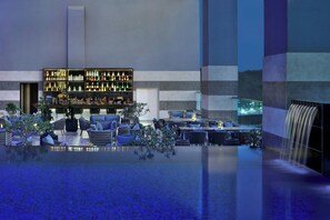 A modern bar area with a variety of bottles and a seating area with tables and chairs.