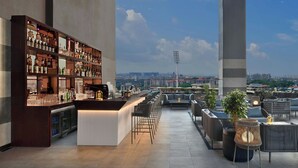 Un bar en la azotea con barra, zona de estar y un amplio estante con botellas.