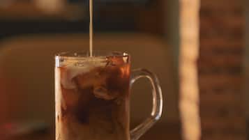 Una taza de vidrio transparente sobre una superficie de madera, con un líquido siendo servido.