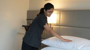 Una habitación de hotel con una cama bien hecha, una lámpara de noche y un cabecero moderno.