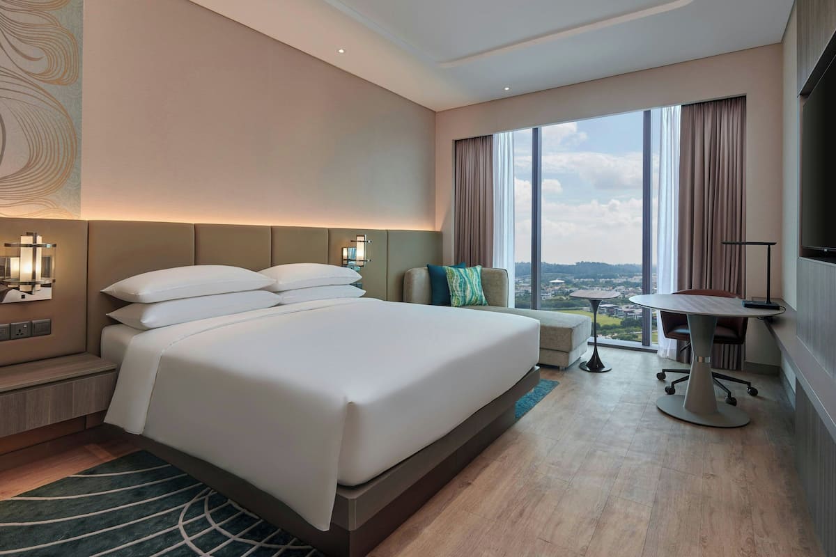 Una habitación de hotel moderna con una cama grande, un escritorio y vistas a la ciudad.