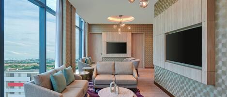 Una sala de estar moderna con un televisor grande, asientos cómodos y vistas a la ciudad.