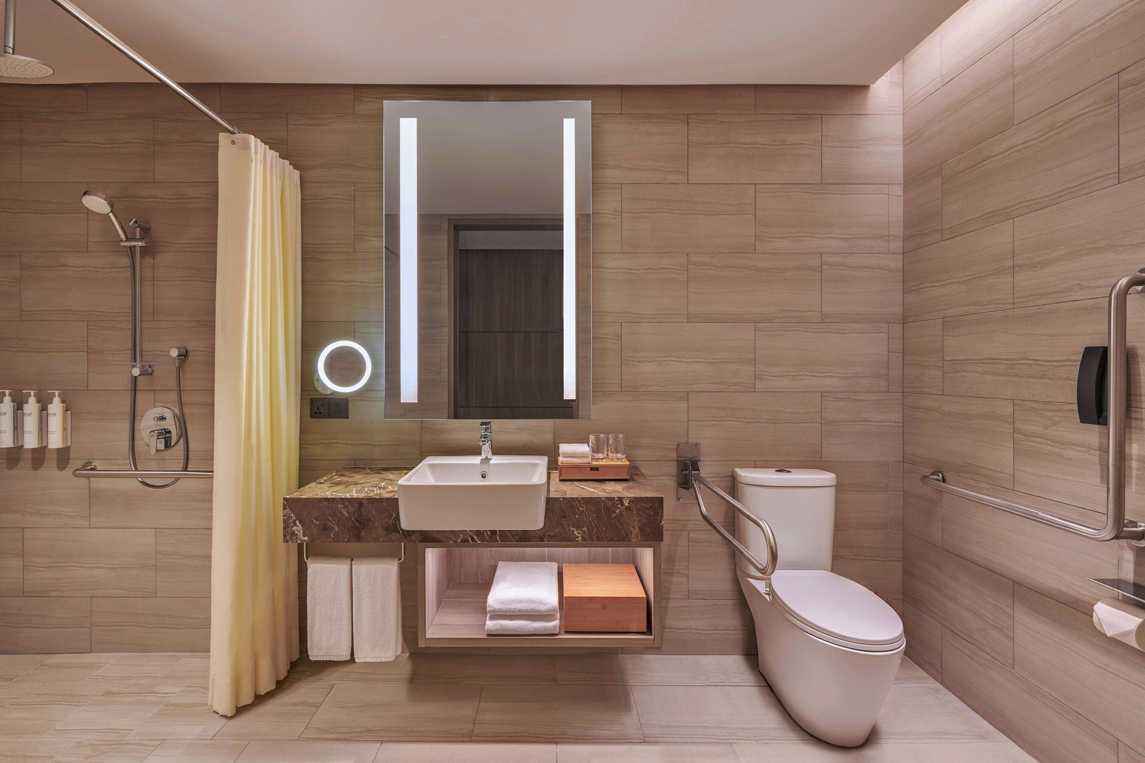 A modern bathroom with a sink, mirror, toilet, and shower.