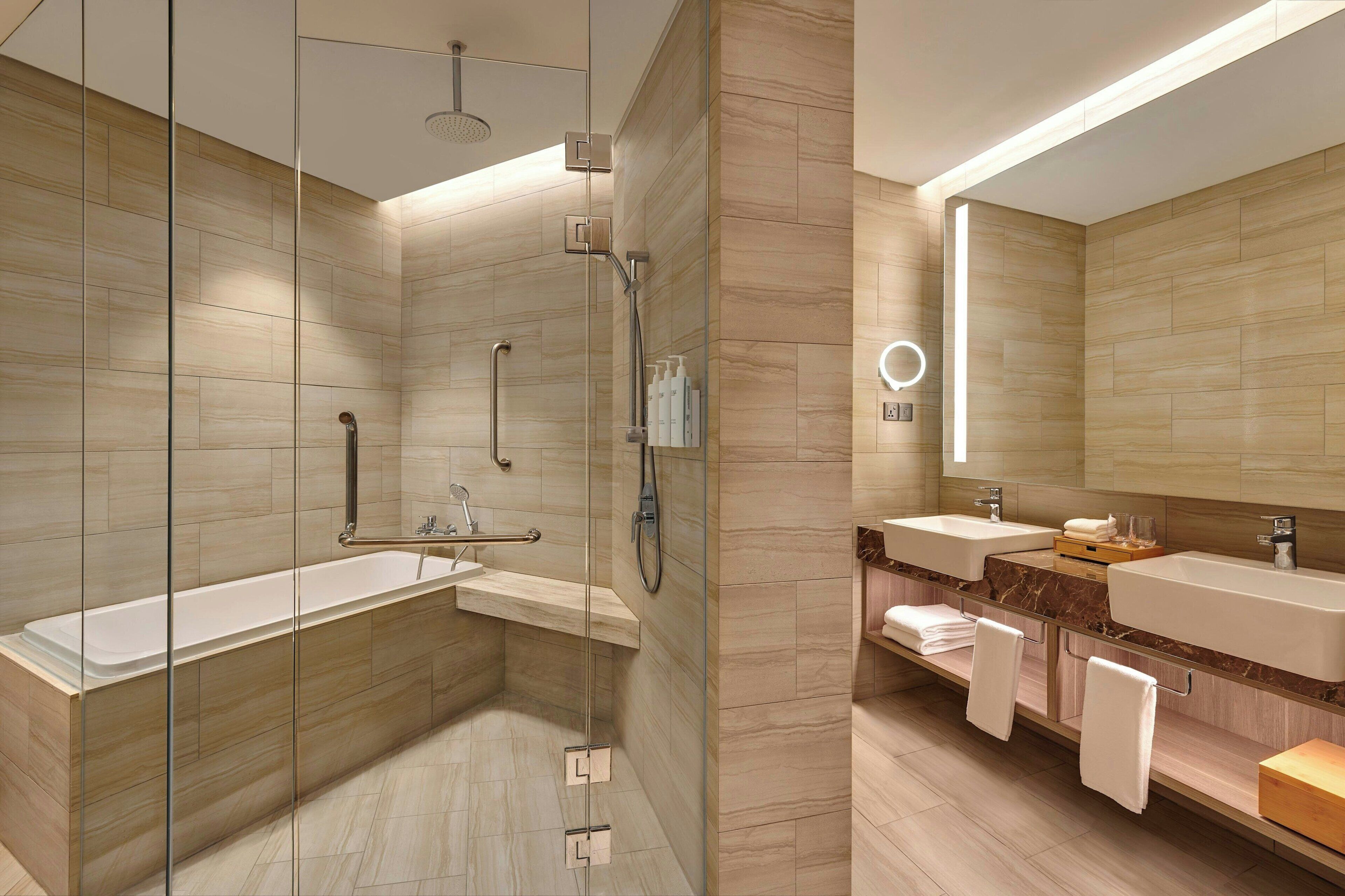 A modern bathroom with a glass-enclosed shower, a freestanding bathtub, and a vanity with two sinks.