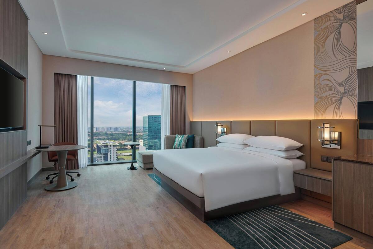 Una habitación de hotel con una cama grande, un escritorio y vistas a la ciudad.