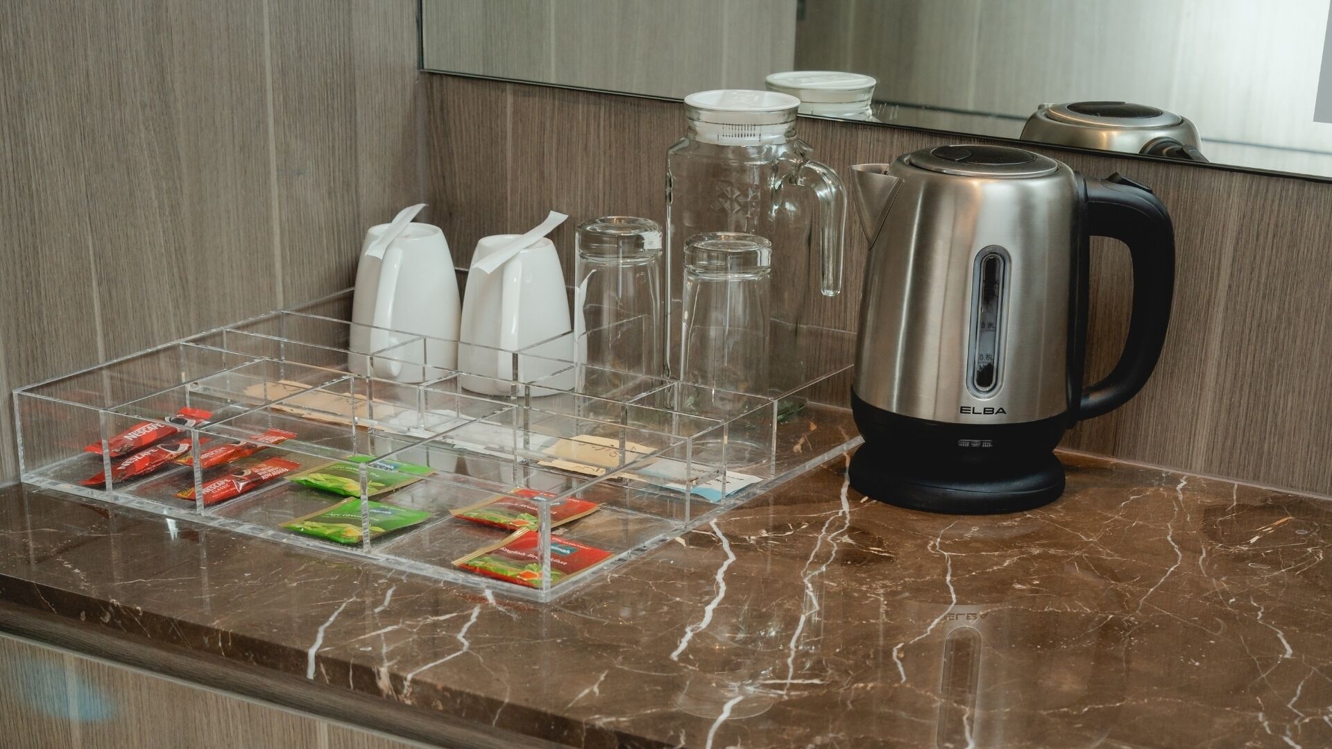 Un comptoir de cuisine avec une machine à café, un récipient en verre et un organisateur transparent contenant des collations.