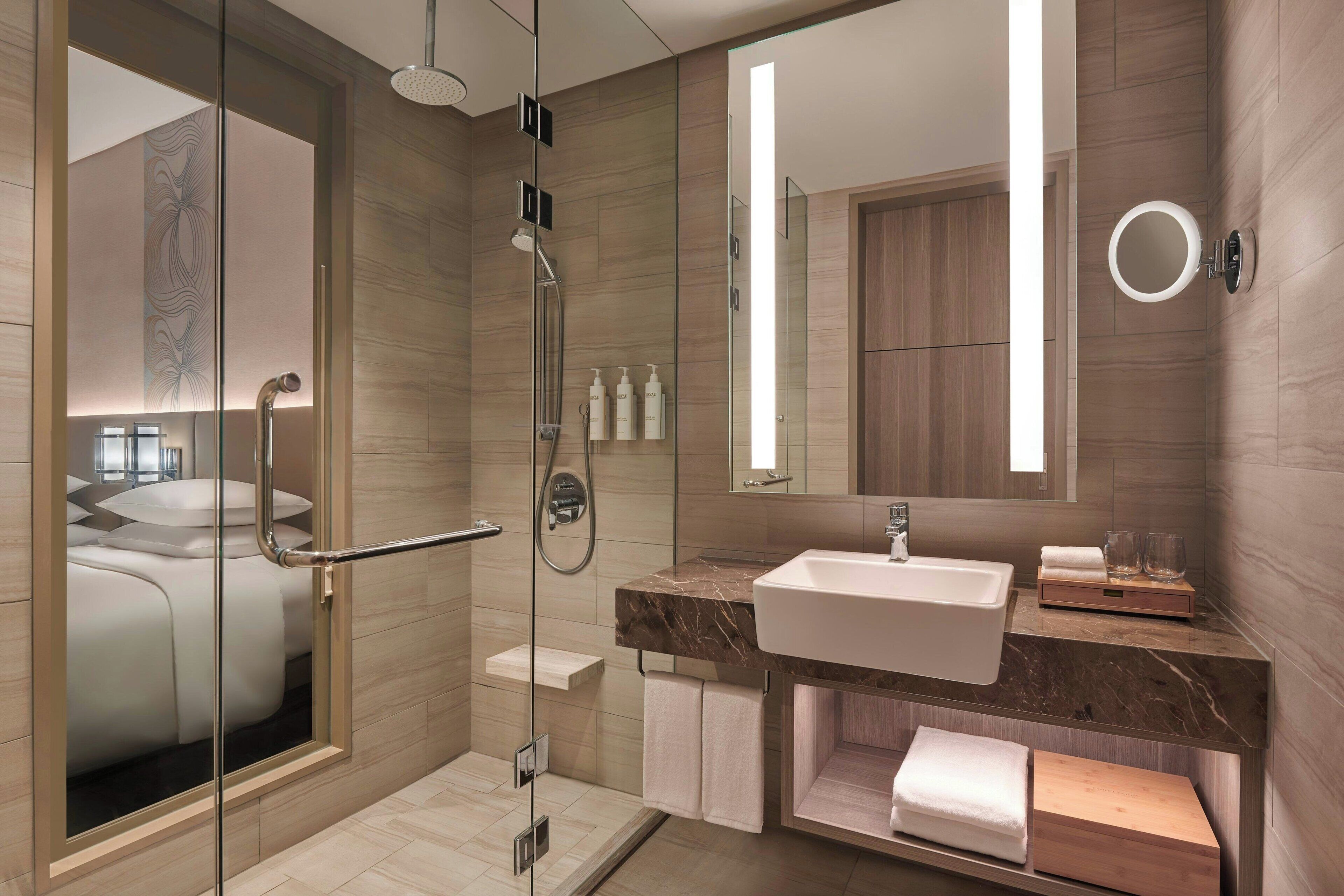 A modern bathroom with a glass-enclosed shower, a marble sink, and a large mirror.