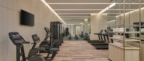 A modern gym with treadmills, elliptical machines, and weight stations.