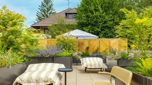A patio with two sun loungers, a small round table, and a bench. - June Six Salzburg, a Tribute Portfolio Hotel (Salzburg)