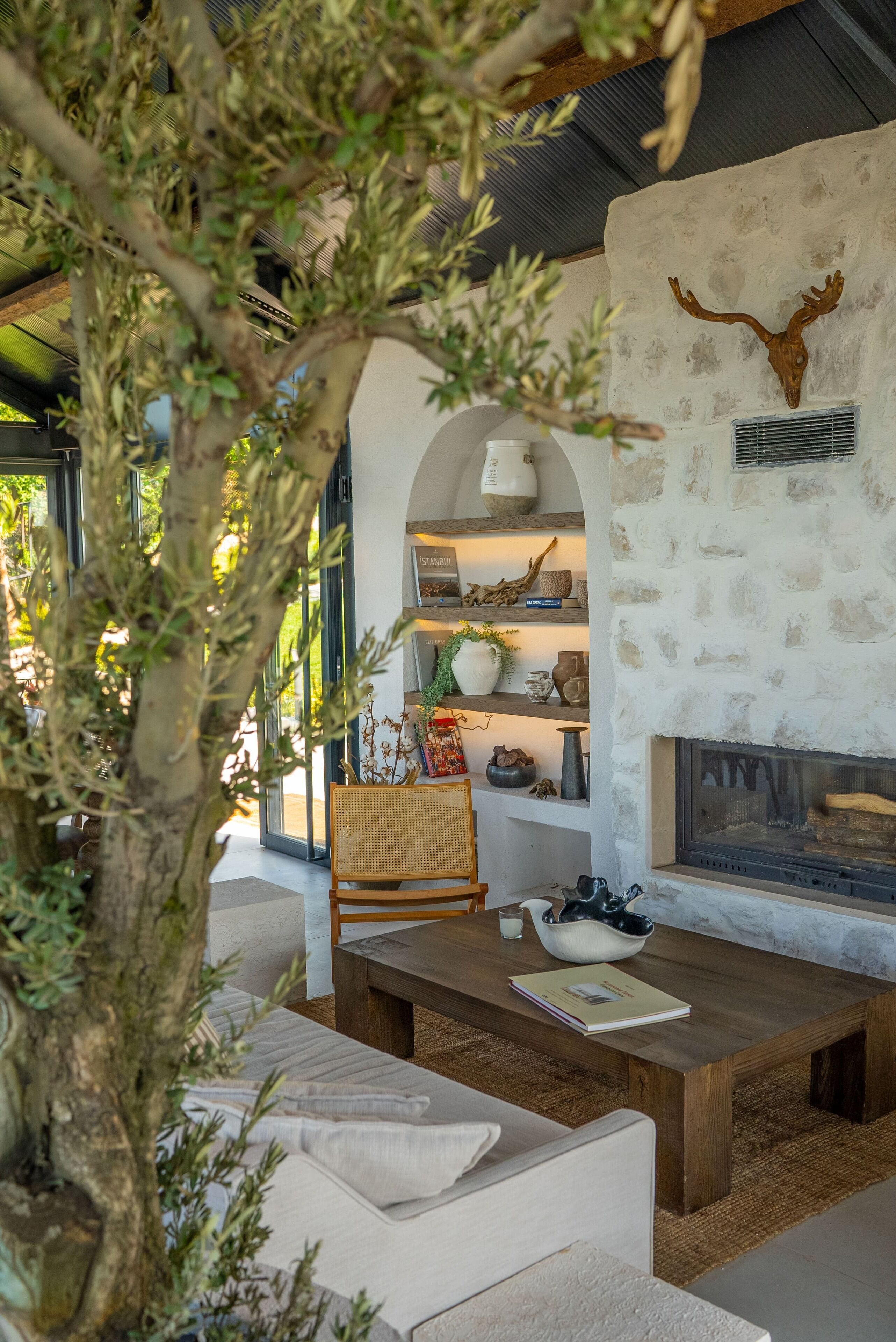 Una sala de estar acogedora con chimenea de piedra, muebles de madera y una estantería con adornos.