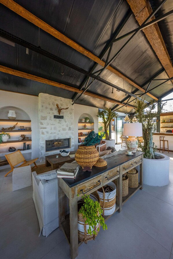 Un salón amplio con chimenea de piedra, muebles de madera y plantas en macetas.